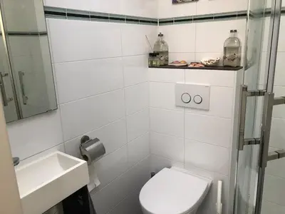a white bathroom with a toilet and a sink at Family beach house in Egmond aan Zee