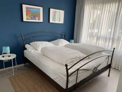 a bedroom with a bed with a blue wall at Kuifje aan Zee in Egmond aan Zee