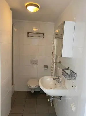 a white bathroom with a toilet and a sink at Kuifje aan Zee in Egmond aan Zee