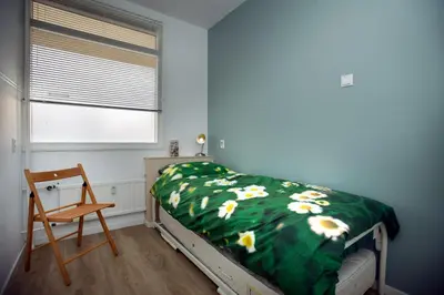 a bedroom with a bed with a green blanket with flowers at bij Miep in Egmond aan Zee