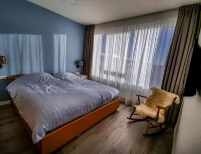 a bedroom with a bed and a chair and a window at de Vuurtoren in Egmond aan Zee