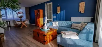 a blue living room with a couch and a table at de Vuurtoren in Egmond aan Zee