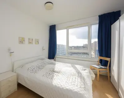a bedroom with a white bed and a window at de Vloedlijn in Egmond aan Zee