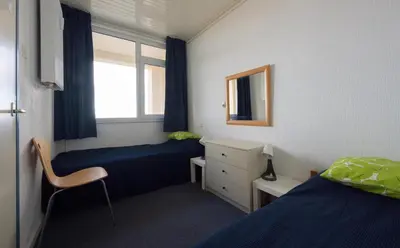 a room with two beds and a desk and a window at de Vloedlijn in Egmond aan Zee