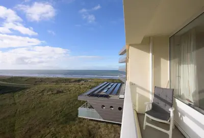 a balcony with a chair and a view of the ocean at de Vloedlijn in Egmond aan Zee
