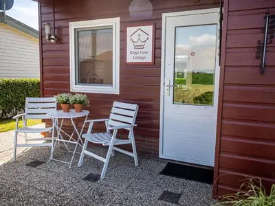 a table and chairs outside of a building with a door at Kings View Cottage, Helemaal vernieuwd 2025 in Warmenhuizen