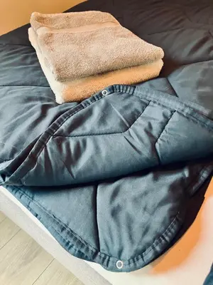 a pile of clothes sitting on top of a bed at Kings View Cottage, Helemaal vernieuwd 2025 in Warmenhuizen