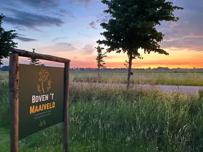a sign in a field with a tree and a sunset at Luxe Wikkelhouse met hottub 'Dompel' in Hoogwoud