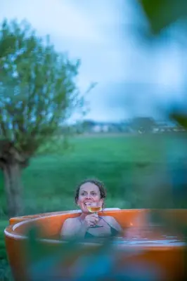 a woman sitting in an orange bath tub with aasteryastery at Luxe Wikkelhouse met hottub 'Dompel' in Hoogwoud