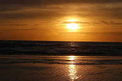 a sunset on the beach with the ocean at Pat's home in Alkmaar