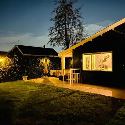 a house with a deck in the yard at night at Nice chalet near Reeuwijkse plassen in Reeuwijk