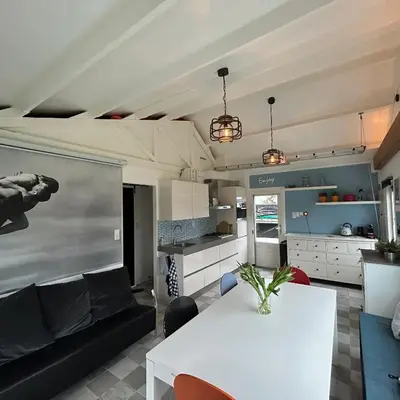 a living room with a white table and a kitchen at Nice chalet near Reeuwijkse plassen in Reeuwijk