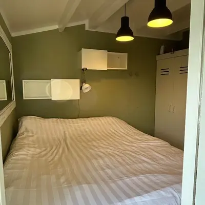 a bed in a bedroom with green walls and lights at Nice chalet near Reeuwijkse plassen in Reeuwijk