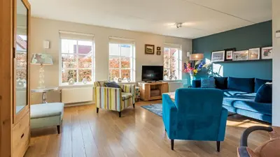 a living room with a blue couch and chairs at Klavertje vier in Schoorl