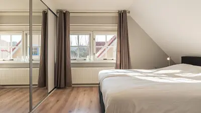 a bedroom with a bed and two windows at Klavertje vier in Schoorl