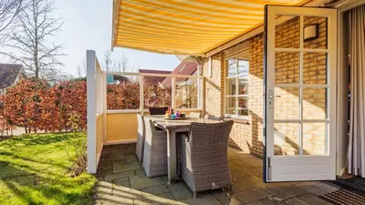 a patio with a table and chairs and a window at Klavertje vier in Schoorl