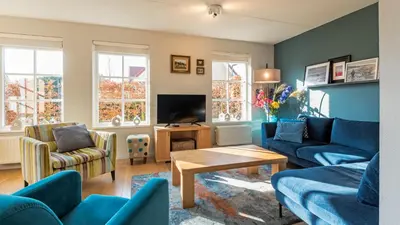 a living room with blue couches and a tv at Klavertje vier in Schoorl