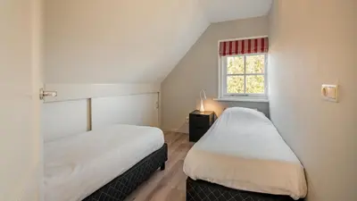 two beds in a small room with a window at Klavertje vier in Schoorl