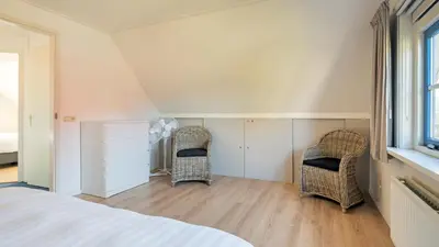 a bedroom with two wicker chairs and a bed at De Zeemeeuw in Schoorl
