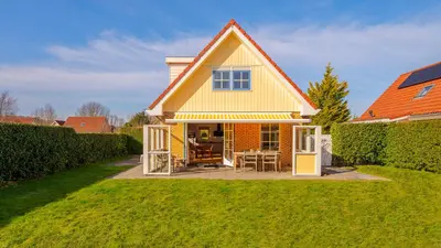 a yellow house with an orange roof at De Zeemeeuw in Schoorl