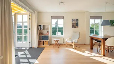 a living room with a table and chairs and windows at De Zeemeeuw in Schoorl