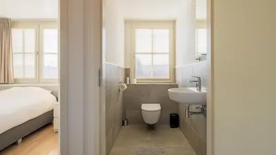 a bathroom with a sink and a toilet and a bed at De Zeemeeuw in Schoorl