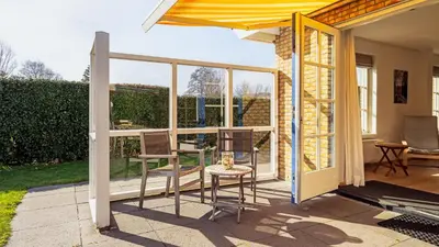 a patio with a table and chairs and windows at De Zeemeeuw in Schoorl