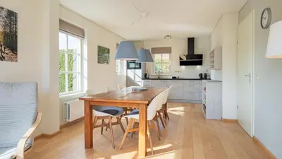 a kitchen and dining room with a wooden table and chairs at De Zeemeeuw in Schoorl
