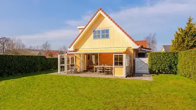 a yellow house with a lawn in front of it at De Zeemeeuw in Schoorl