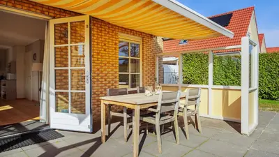 a patio with a wooden table and chairs at De Zeemeeuw in Schoorl