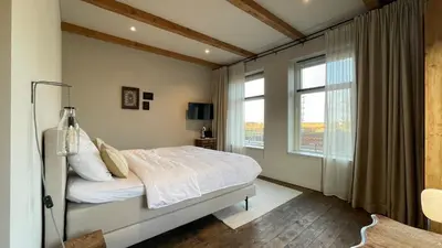 a bedroom with a bed and a large window at Het Kerspel in Hoogkarspel