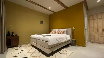 a bedroom with a bed and a yellow wall at Het Kerspel in Hoogkarspel