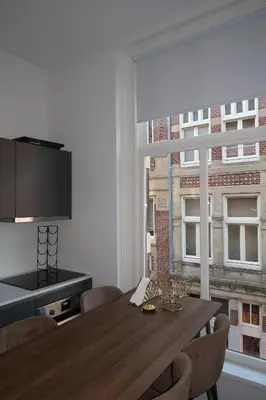 a dining room with a table and a large window at Appartement Rokin in Amsterdam