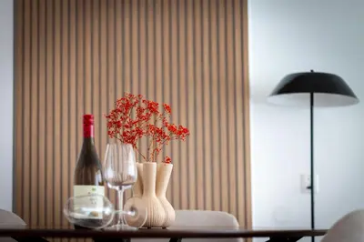 a table with two bottles and two vases with red flowers at Lovina Beach House by Urban Home Stay in Egmond aan Zee