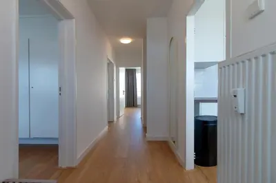 an empty hallway with white walls and wooden floors at Lovina Beach House by Urban Home Stay in Egmond aan Zee