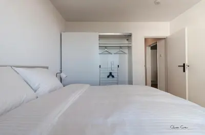 a white bed in a white bedroom with a closet at Lovina Beach House by Urban Home Stay in Egmond aan Zee