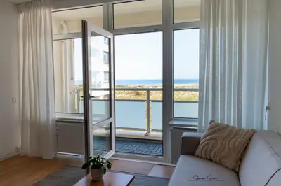 a living room with a couch and a large window at Lovina Beach House by Urban Home Stay in Egmond aan Zee
