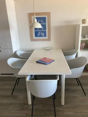 a white dining room table with chairs and a book on it at Zonnehoek 71 in Egmond aan Zee