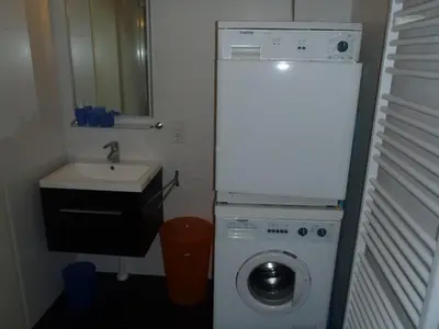 a small bathroom with a washing machine and a sink at Zonnehoek 71 in Egmond aan Zee