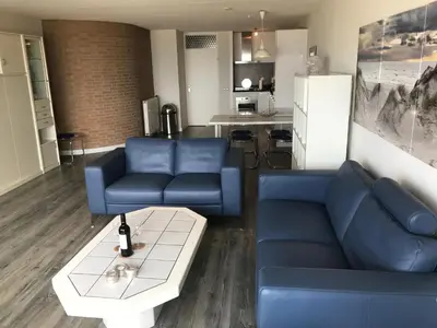 a living room with a blue couch and a table at Zonnehoek 71 in Egmond aan Zee
