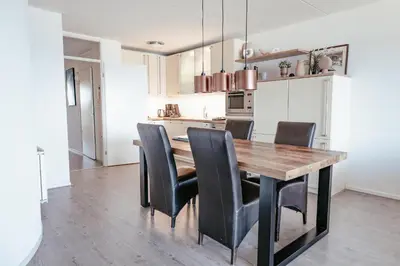a kitchen with a wooden table and black chairs at Zonnehoek 75 in Egmond aan Zee
