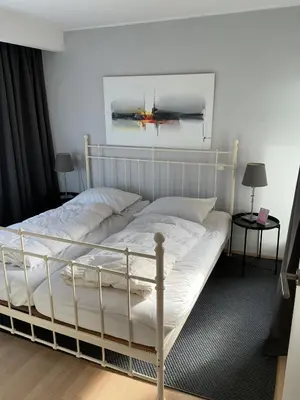 a bedroom with a white bed with a painting on the wall at Zonnehoek 77 in Egmond aan Zee