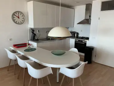 a kitchen with a white table and chairs and a clock at Zonnehoek 77 in Egmond aan Zee