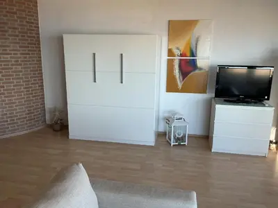 a living room with a white cabinet and a tv at Zonnehoek 77 in Egmond aan Zee