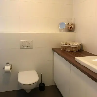 a white bathroom with a toilet and a sink at Zonnehoek 77 in Egmond aan Zee