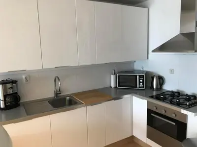 a kitchen with white cabinets and a sink and a microwave at Zonnehoek 77 in Egmond aan Zee