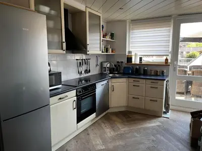 a kitchen with white appliances and a large window at The Lighthouse in Egmond aan Zee