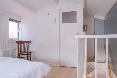 a bedroom with a bed and a chair and a window at Fay in Egmond aan Zee