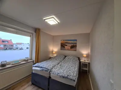 a bedroom with a bed and a large window at Atlantis 14c in Egmond aan Zee