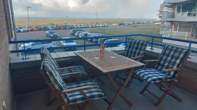 a table and chairs on a balcony with a view of a parking lot at Atlantis 14c in Egmond aan Zee